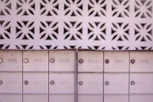 Two banks of numbered metal mailboxes set against a patterned white breeze-block wall.